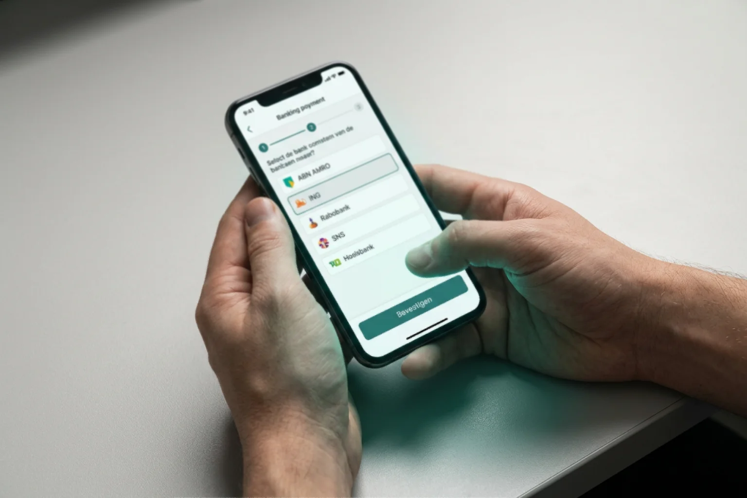Persoon kiest de eigen bank en bevestigt een iDEAL-storting stap voor stap op een mobiele telefoon